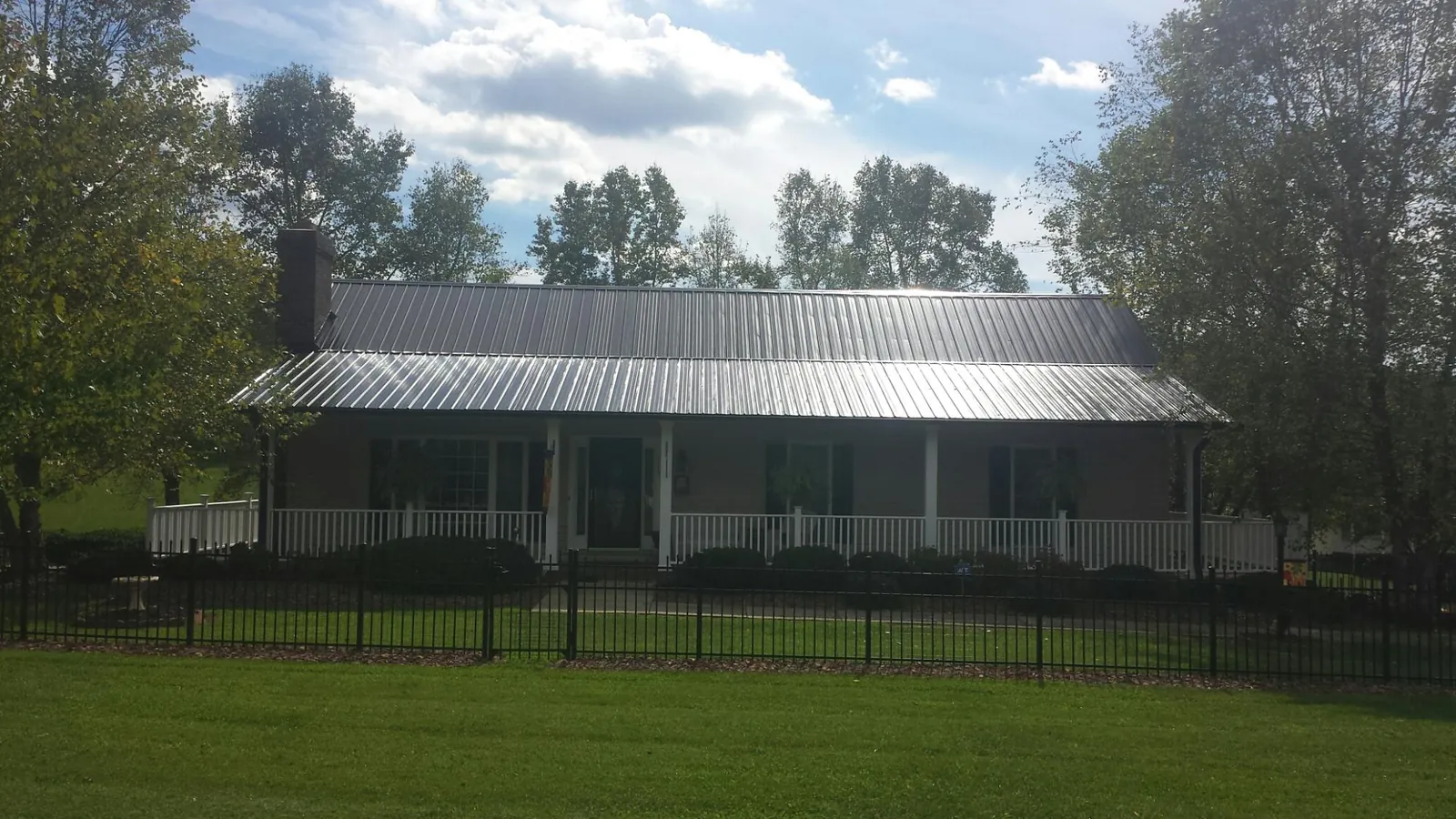 Gray metal roof on a brick ranch with a full width front porch — Gutter Guard Installation work by our crew in Rifle