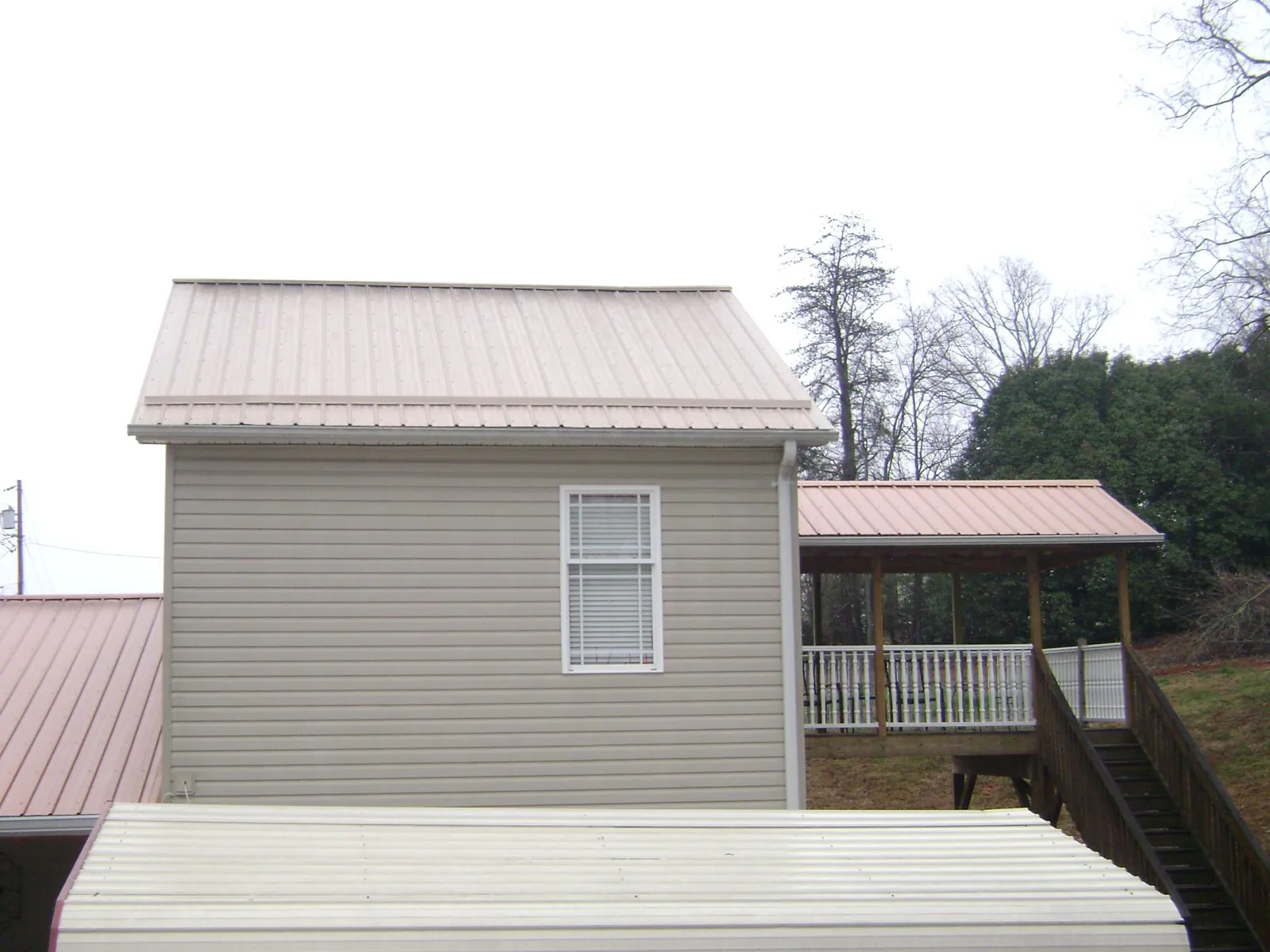 Tan metal roofs on a two story addition and attached porch, from a Roof Replacement job in Rifle