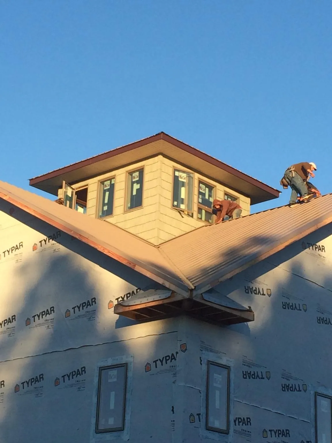 Roofers working around a rooftop cupola on a new metal roof at sunset — Roof Waterproofing in Rifle by Roofing Brothers
